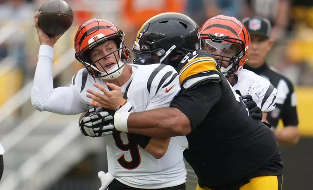 Cincinnati Bengals quarterback Joe Burrow, left, throws as he is tackled by Pittsburgh Steelers defensive tackle Cameron Heyward, right, during the second half of an NFL football game in Pittsburgh, Sunday, Sept. 27, 2026. (AP Photo/Gene J. Puskar)