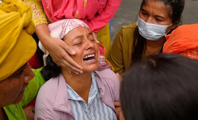Relatives console Muna Khadka, center, who lost her son Aayush Khada in flash floods, at a cremation ground in Chitwan, Nepal, Monday, Aug. 31, 2026. (AP Photo/Dar Yasin) CORRECTION: Corrects to clarify that this was at a separate cremation ground and not during a mass burial.