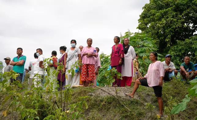 Onlookers watch as volunteers and rescuers carry the body of a flash flood victim for mass burial in Chitwan, Nepal, Monday, Aug. 31, 2026. (AP Photo/Dar Yasin)