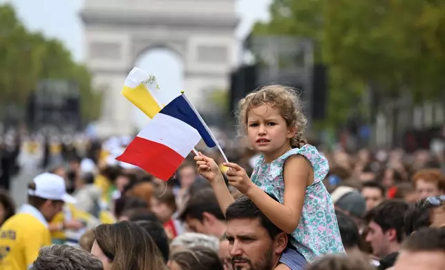 People wait for Pope Leo XIV on the Champs Elysees avenue before a mass at the Place de la Concorde in Paris, Saturday, Sept. 26, 2026. (AP Photo/Emma Da Silva)