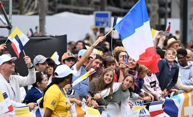 People wait for Pope Leo XIV on the Champs Elysees avenue before a mass at the Place de la Concorde in Paris, Saturday, Sept. 26, 2026. (AP Photo/Emma Da Silva)