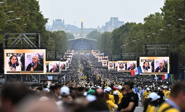 People wait for Pope Leo XIV on the Champs Elysees avenue before a mass at Place de la Concorde in Paris, Saturday, Sept. 26, 2026. (AP Photo/Emma Da Silva)