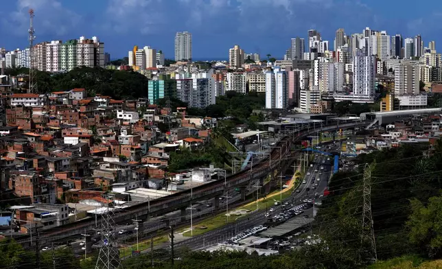 A low-income residential community, left, stands in contrast to high-rise residential buildings with an elevated metro line cutting through the urban landscape in Salvador, Bahia state, Brazil, Saturday, Aug. 29, 2026. (AP Photo/Eraldo Peres)
