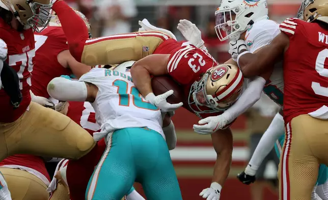 San Francisco 49ers running back Christian McCaffrey (23) jumps over Miami Dolphins linebacker Jacob Rodriguez (10) to score during the second half of an NFL football game in Santa Clara, Calif., Sunday, Sept. 20, 2026. (AP Photo/Jed Jacobsohn)