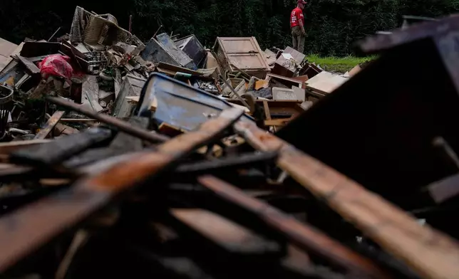 FILE - A man stands near a pile of debris as residents clean up in Fleming-Neon, Ky., Aug. 5, 2022, after massive flooding the previous week. (AP Photo/Brynn Anderson, File)