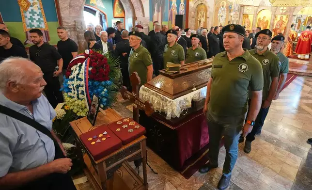 People line up to pay their respects as Serbian war veterans stand around the coffin of the former Bosnian Serb army commander Ratko Mladic, who died last week while serving a life sentence for genocide and other atrocities during the war in Bosnia, at the St. Luka Church, in Belgrade, Serbia, Monday, Sept. 7, 2026. (AP Photo/Darko Vojinovic)
