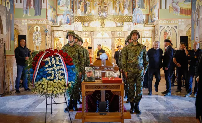 A man touches the cross as Serbian national military servicemen stand around the coffin of the former Bosnian Serb army commander Ratko Mladic, who died last week while serving a life sentence for genocide and other atrocities during the war in Bosnia, at the St. Luka Church, in Belgrade, Serbia, Monday, Sept. 7, 2026. (AP Photo/Marko Drobnjakovic)