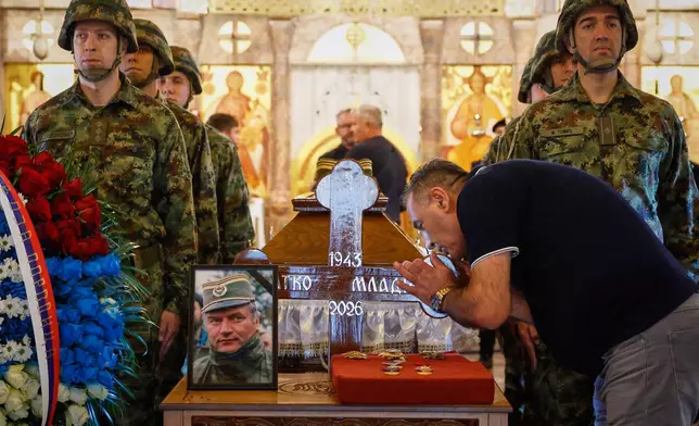 A man touches the cross as Serbian national military servicemen stand around the coffin of the former Bosnian Serb army commander Ratko Mladic, who died last week while serving a life sentence for genocide and other atrocities during the war in Bosnia, at the St. Luka Church, in Belgrade, Serbia, Monday, Sept. 7, 2026. (AP Photo/Marko Drobnjakovic)