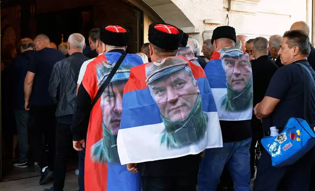 People line up to pay their respects to the former Bosnian Serb army commander Ratko Mladic, seen on the flags, who died last week while serving a life sentence for genocide and other atrocities during the war in Bosnia, at the St. Luka Church, in Belgrade, Serbia, Monday, Sept. 7, 2026. (AP Photo/Marko Drobnjakovic)
