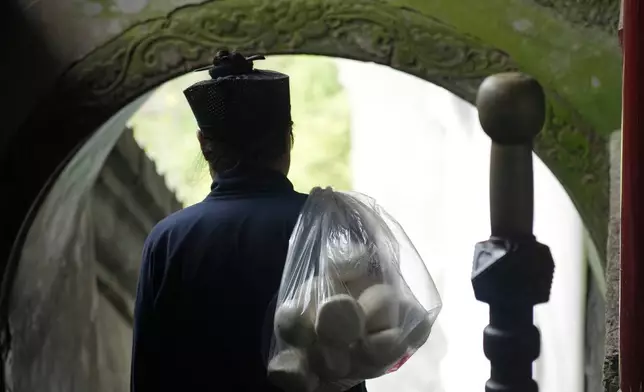 A Taoist priest walks with a bag of buns over his shoulder near the Golden Hall in Wudang Mountains in central China's Hubei Province on Sept. 3, 2026. (AP Photo/Achmad Ibrahim)