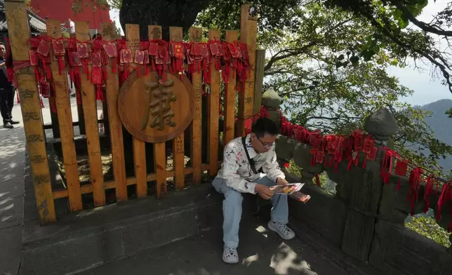 A visitor sits near wishes written on red cards near the Golden Hall in Wudang Mountains in central China's Hubei Province on Sept. 3, 2026. (AP Photo/Achmad Ibrahim)