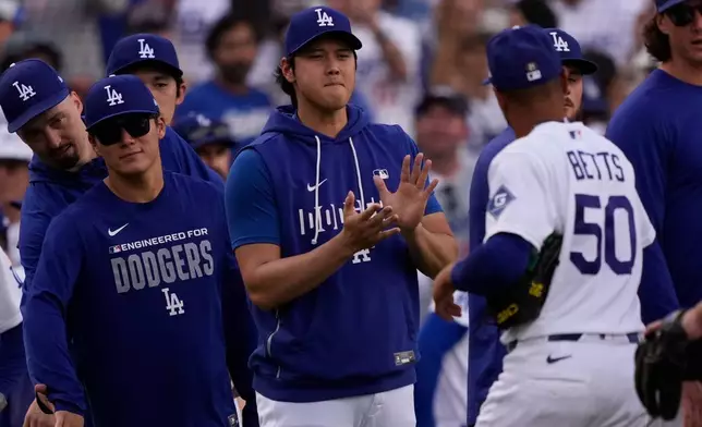 Los Angeles Dodgers' Mookie Betts, right, is congratulated by Shohei Ohtani, center, and Yoshinobu Yamamoto after the Dodgers defeated the San Francisco Giants in a baseball game Sunday, Sept. 20, 2026, in Los Angeles. (AP Photo/Mark J. Terrill)