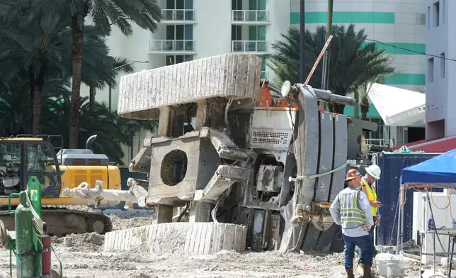 Workers stand near the site where a large construction crane collapsed, Monday, Sept. 14, 2026, in Miami. (AP Photo/Marta Lavandier)
