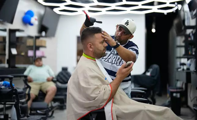 Barber Diego Contreras cuts the hair of fellow Venezuelan Diego Parra on Wednesday, July 15, 2026, in Midvale, Utah. (AP Photo/Gregory Bull)