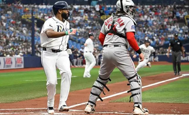 Tampa Bay Rays' Junior Caminero, left, scores off a single hit by Chandler Simpson as Boston Red Sox catcher Adley Rutschman, right, looks on during the first inning of a baseball game, Sunday, Sept. 20, 2026, in St. Petersburg, Fla. (AP Photo/Phelan M. Ebenhack)