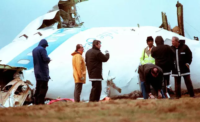 FILE - Unidentified crash investigators inspect the nose section of the crashed Pan Am flight 103, a Boeing 747 airliner in a field near Lockerbie, Scotland, Dec. 23, 1988. (AP Photo/Dave Caulkin, File)