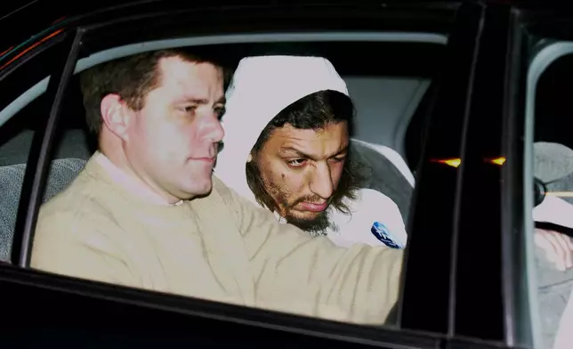 FILE - An FBI agent, left, sits next to a suspect identified by authorities as Richard Reid as he is transported in a car from State Police barracks at Logan International Airport in Boston, Dec. 22, 2001. (AP Photo/Elise Amendola, File)