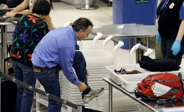 FILE - An airline passenger pulls off his shoes to be scanned as he prepares to go through a security checkpoint at Seattle-Tacoma International Airport, Jan. 4, 2010, in SeaTac, Wash. (AP Photo/Elaine Thompson, File)