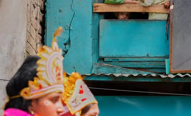 A Kashmiri family watch from the window of their house as children dressed as the Hindu deities Krishna and Radha take part in a procession celebrating Janmashtami, the Hindu festival marking the birth of the god Krishna, in Srinagar, Indian-controlled Kashmir, Friday, Sept. 4, 2026. (AP Photo/Mukhtar Khan)