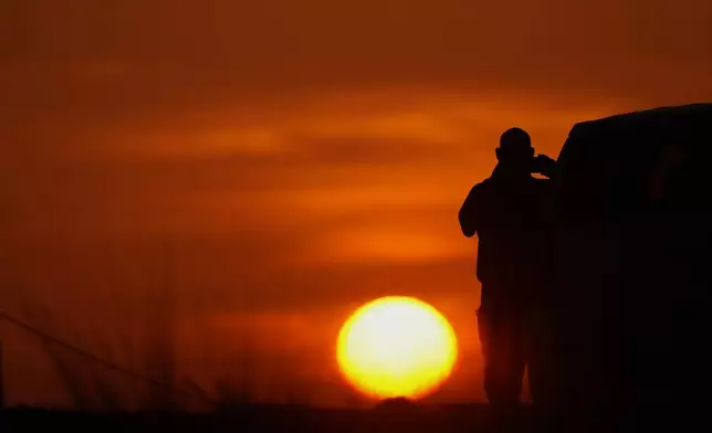 A U.S. Border Patrol agent takes a picture of the sunrise next to a section of border wall at the Santa Ana Wildlife Refuge in Alamo, Texas, Tuesday, Aug. 25, 2026. (AP Photo/Eric Gay)