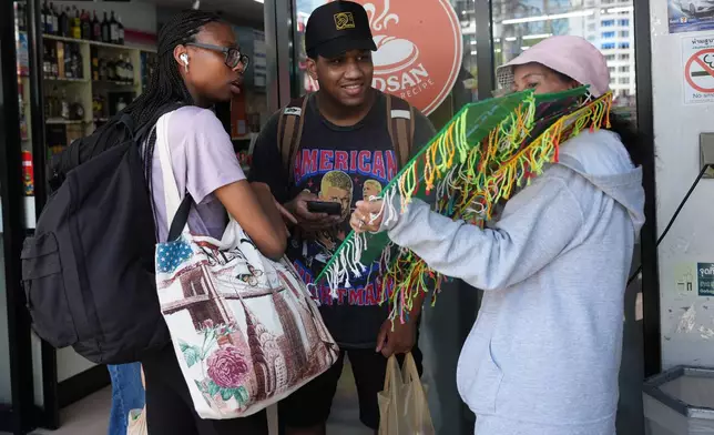 Crew members of the USS Abraham Lincoln talk to a souvenir vendor in Pattaya, Thailand, Thursday, Sept. 3, 2026. (AP Photo/Sakchai Lalit)