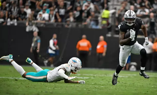 Las Vegas Raiders running back Mike Washington Jr. (4) runs from Miami Dolphins cornerback Juju Brents during the first half of an NFL football game, Sunday, Sept. 13, 2026, in Las Vegas. (AP Photo/David Becker)