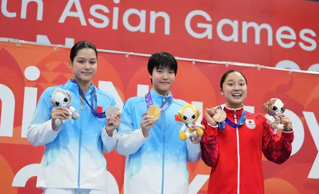 Gold medalist Yu Zidi of China, center, flanked by silver medalist Yu Yiting of China, left, and bronze medalist Mio Narita of Japan pose on the podium after the women's 200-meter individual medley final in swimming at the Asian Games in Tokyo, Japan, Monday, Sept. 21, 2026. (AP Photo/Hiro Komae)