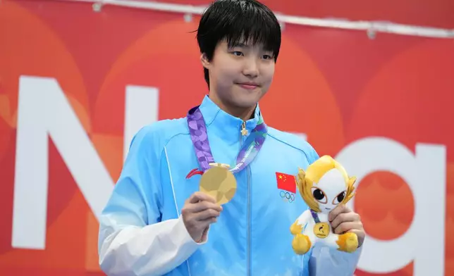 Gold medalist Yu Zidi of China poses on the podium after the women's 200-meter individual medley final in swimming at the Asian Games in Tokyo, Japan, Monday, Sept. 21, 2026. (AP Photo/Hiro Komae)
