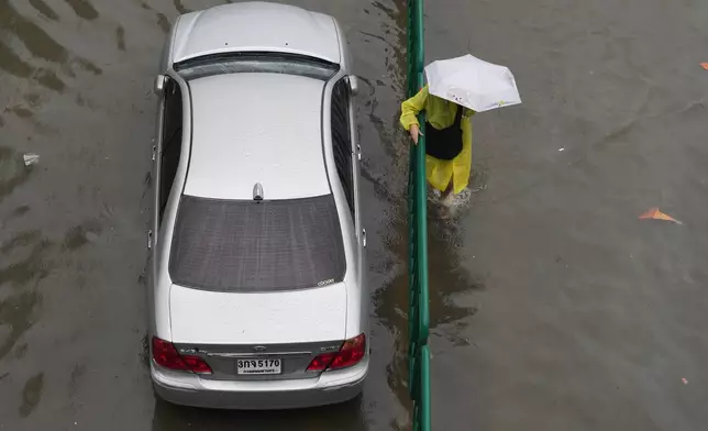 A woman wades through floodwaters after heavy rain in Bangkok, Thailand Saturday, Sept. 26, 2026. (AP Photo/Sakchai Lalit)