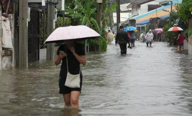 People wade through floodwaters after heavy rain in Bangkok, Thailand, Saturday, Sept. 26, 2026. (AP Photo/Sakchai Lalit)