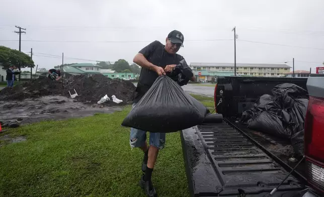 Darren Montalvo loads into the bed of his truck sand bags he will use to help keep water out of his restaurant as Hurricane Nolo approaches in Hilo, Hawaii, Friday, Sept. 25, 2026. (AP Photo/Gregory Bull)