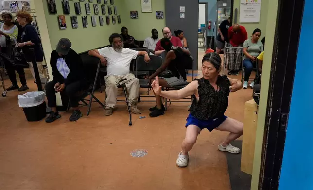 Yun Gao of China practices tai chi as she waits to receive food at Valley Interfaith Community Resource Center in Lockland, Ohio, Friday, July 10, 2026. (AP Photo/Carolyn Kaster)