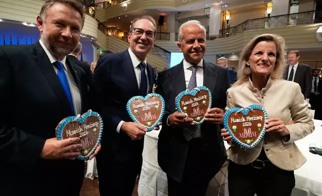 German Interior Minister Alexander Dobrindt, second left, Parliamentary State Secretary Daniela Ludwig, right, Poland's Minister of the Interior and for Administration Marcin Kierwinski, left, and Italian Interior Minister Matteo Piantedosi pose with gingerbread hearts before the Munich Migration Meeting in Munich, Germany, Saturday, Sept. 26, 2026. (AP Photo/Matthias Schrader)