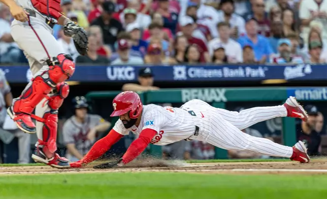 Philadelphia Phillies Derek Hill, right, scores past Atlanta Braves catcher Drake Baldwin, left, on an RBI hit by Kyle Schwarber during the second inning of a baseball game, Saturday, Sept. 5, 2026, in Philadelphia. (AP Photo/Laurence Kesterson)