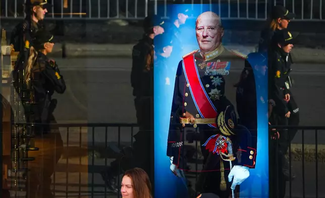 Police officers reflected in a window with a display showing Norway's late King Harald V prior to his funeral in Oslo, Norway, Wednesday, Sept. 9, 2026. (AP Photo/Markus Schreiber)