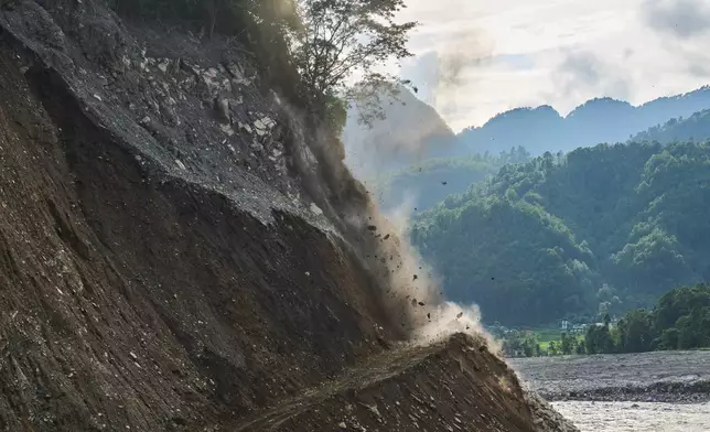 Rocks tumble from a hillside after controlled explosives are used to clear a route for a temporary road reconnecting towns and villages after flash floods damaged the existing road in Nepal's Nuwakot district, Wednesday, Sept. 23, 2026. (AP Photo/Niranjan Shrestha)