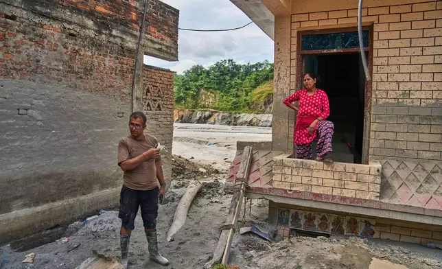 Narayan Prasad Nepal, left, stands outside his damaged house by a flash flood in Galchi, Nuwakot, Nepal, Wednesday, Sept. 23, 2026. (AP Photo/Niranjan Shrestha)