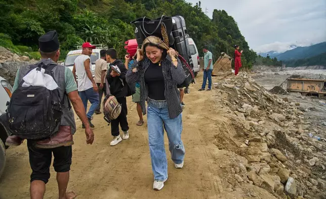 People carry their belongings as they walk toward their villages after flash floods damaged roads in Nepal's Nuwakot district, Wednesday, Sept. 23, 2026. (AP Photo/Niranjan Shrestha)