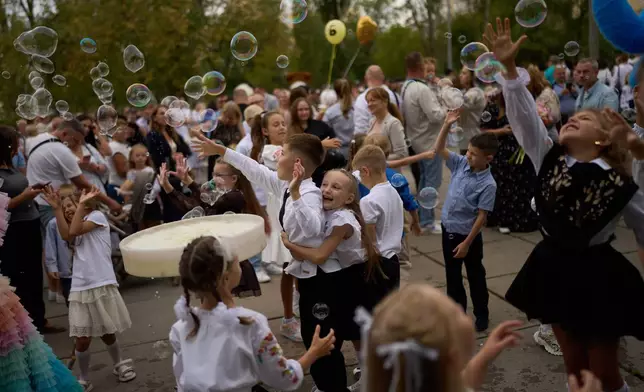 Children play with soap bubbles during the traditional back to school celebrations in Kyiv, Tuesday, Sept. 1, 2026. (AP Photo/Francisco Seco)