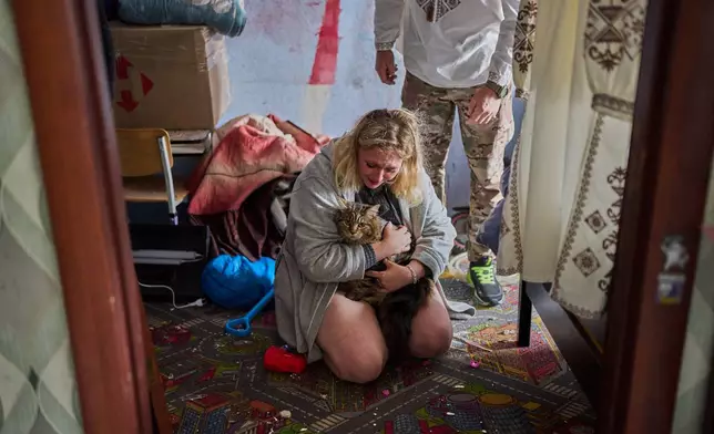 Liudmyla Ryzhak, bottom, and her fiancee Leonid Ryzhak found their lost cat in their damaged apartment following a Russian missile and drone attack in Kyiv, Ukraine, early Tuesday, Sept. 8, 2026, as they get ready for their wedding ceremony. (AP Photo/Francisco Seco)