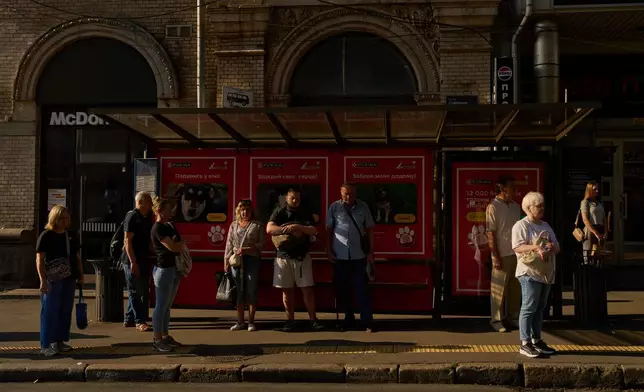 Commuters observe a daily nationwide minute of silence in memory of soldiers killed in the war with Russia, as they wait for a bus in Kyiv, Friday, Sept. 4, 2026. (AP Photo/Francisco Seco)