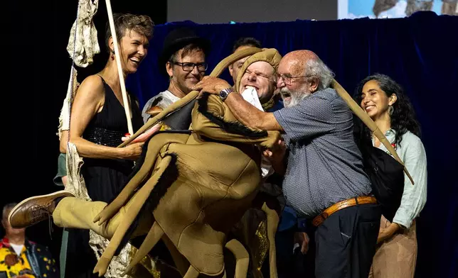 Soil Science Prize Winners, from left, Pia Viviani, Franz Bender, Marcel van der Heijden and Atlant Bieri, receive their prize from Nobel Prize winner Michel Major during the Ig Nobel Prize ceremony held in the Zurich Convention Center in Zurich, Switzerland, on Thursday, Sept. 3, 2026. (Claudio Thoma/Keystone via AP)