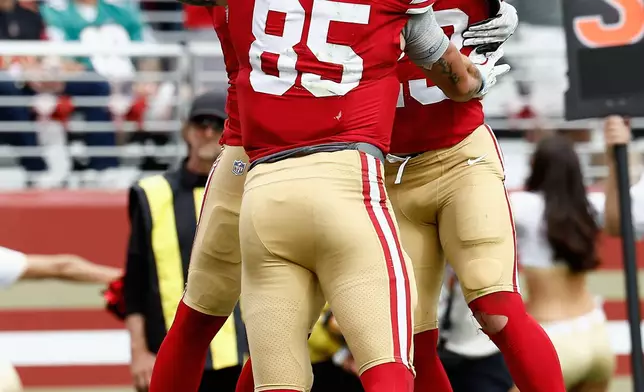 San Francisco 49ers fullback Kyle Juszczyk, top left, is congratulated by tight end George Kittle (85) and running back Christian McCaffrey after scoring against the Miami Dolphins during the second half of an NFL football game in Santa Clara, Calif., Sunday, Sept. 20, 2026. (AP Photo/Kelley L. Cox)
