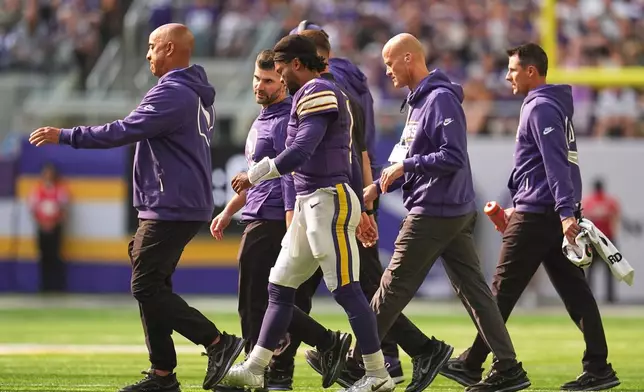 Minnesota Vikings quarterback Kyler Murray, center, walks off the field with staff after suffering an unknown injury during the first half of an NFL football game against the Green Bay Packers Sunday, Sept. 13, 2026, in Minneapolis, Minn. (AP Photo/Abbie Parr)