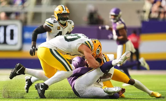 Minnesota Vikings quarterback Kyler Murray, center, is tackled by Green Bay Packers' Lukas van Ness, left, and Javon Bullard, right, during the first half of an NFL football game, Sunday, Sept. 13, 2026, in Minneapolis, Minn. (AP Photo/Abbie Parr)