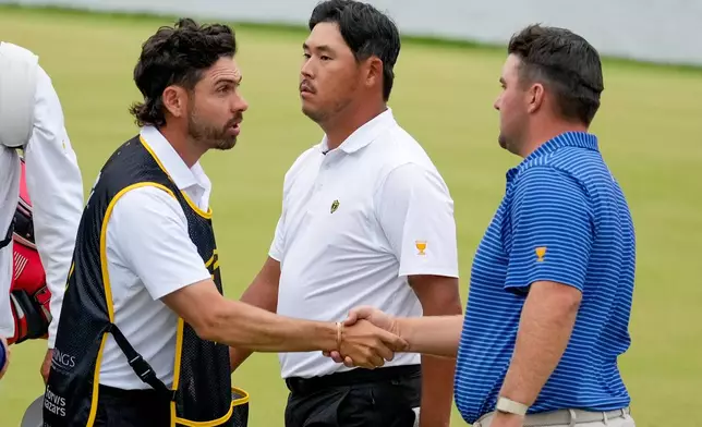 USA teams' Chris Gotterup, right, greets International teams' Tom Kim, of South Korea, center, and his caddie after their first round four-ball match at the Presidents Cup golf tournament at Medinah Country Club, Thursday, Sept. 24, 2026, in Medinah, Ill. (AP Photo/Chris Carlson)