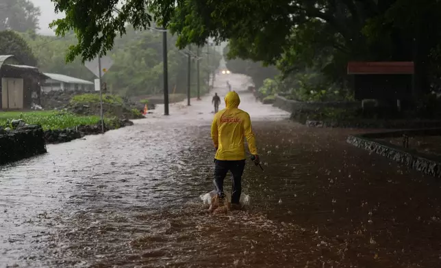 Fire Captain Lui Sales of the Hawaii Fire Department looks for residents to help as rainwater from nearby Hurricane Nolo flood a section of Mamalahoa highway Saturday, Sept. 26, 2026, near Naalehu, Hawaii. (AP Photo/Gregory Bull)