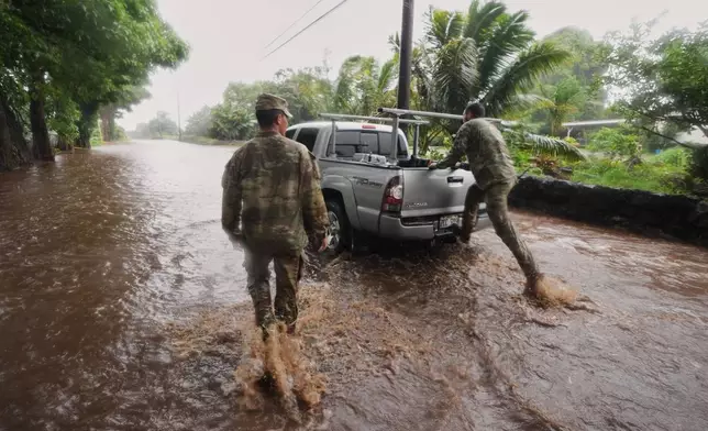 Members of the Hawaii Army National Guard help a resident leave his home as rainwater from nearby Hurricane Nolo floods a section of Mamalahoa highway Saturday, Sept. 26, 2026, near Naalehu, Hawaii. (AP Photo/Gregory Bull)