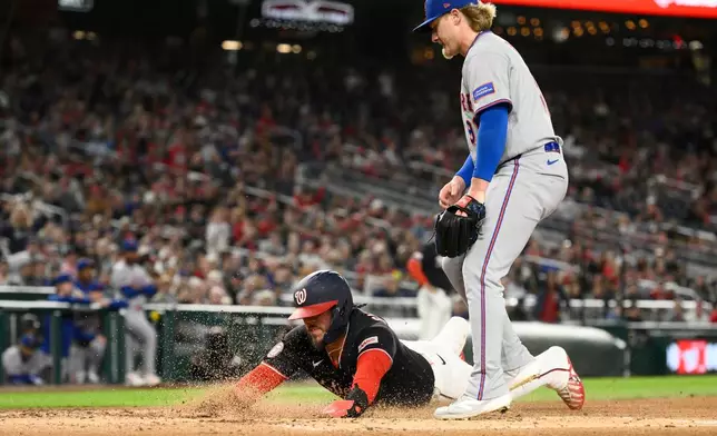 Washington Nationals' Andres Chaparro, bottom, slides home to score on a wild pitch by New York Mets pitcher Jonathan Pintaro, top, during the third inning of a baseball game, Friday, Sept. 25, 2026, in Washington. (AP Photo/Nick Wass)