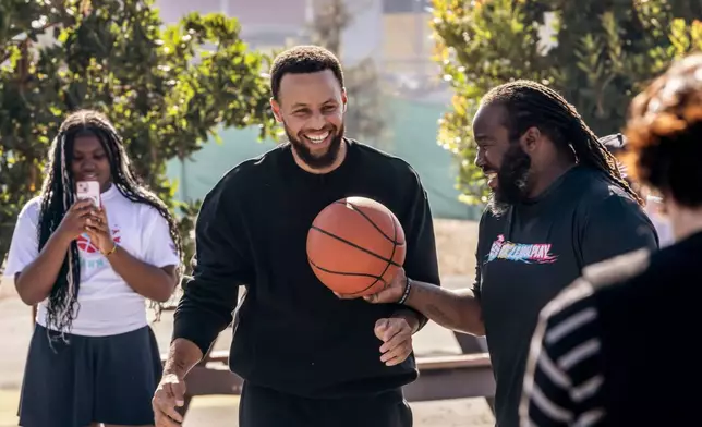 Warriors star Stephen Curry plays a little basketball with students during an event for his Eat.Learn.Play. Foundation at Madison Park Academy Primary in Oakland, Calif., on Wednesday, Sept. 23, 2026. (Carlos Avila Gonzalez/San Francisco Chronicle via AP)